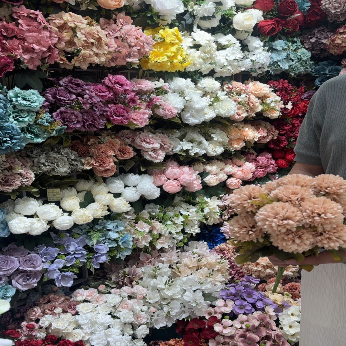 Artificial flower wall display with roses, daisies, tulips, and hydrangeas.