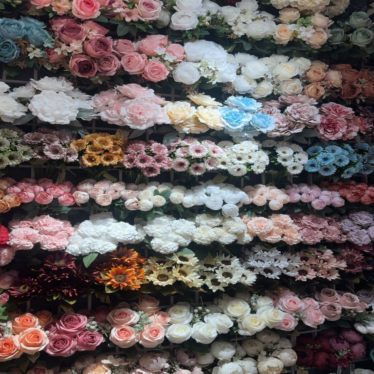 Close-up of artificial peonies, roses, and hydrangeas in various colors.