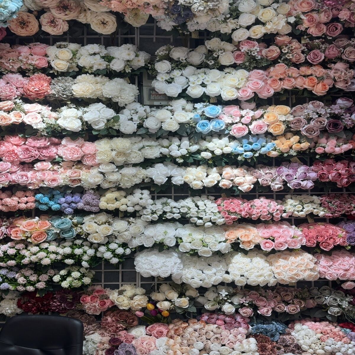 Large display of artificial flowers including roses, hydrangeas, and peonies in multiple colors.